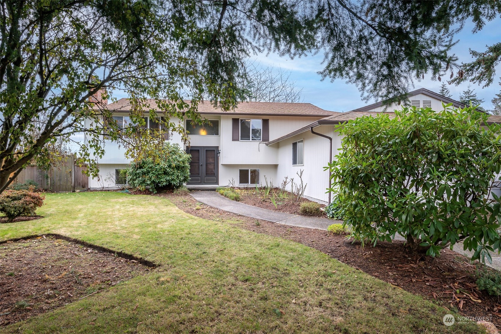 a front view of a house with a garden and trees