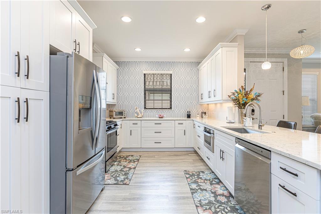 a large white kitchen with a large window and stainless steel appliances