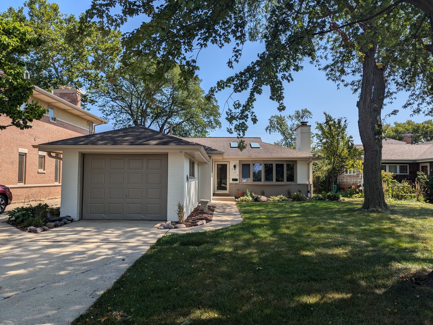 a front view of a house with a garden and trees