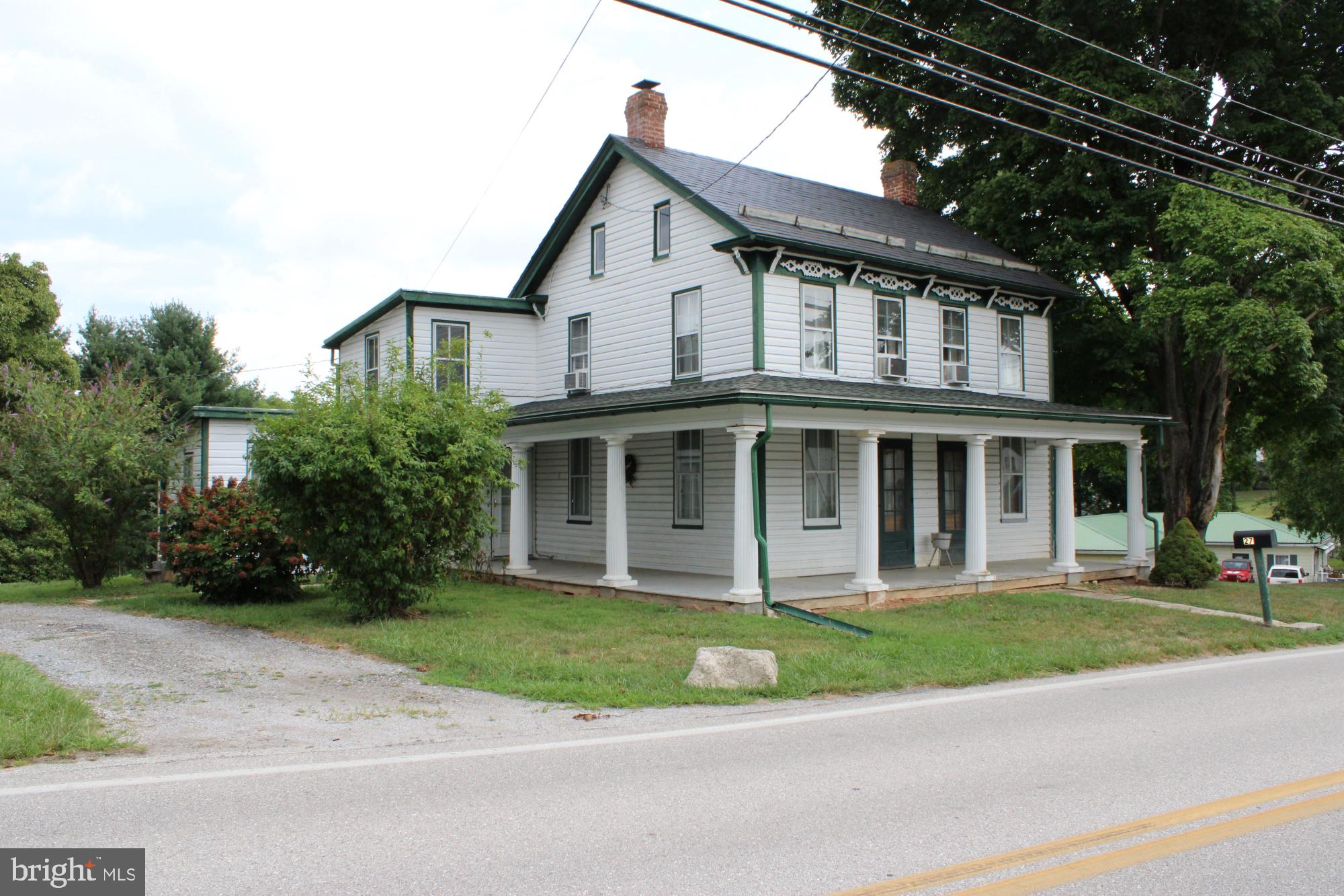 a front view of a house with a garden and trees