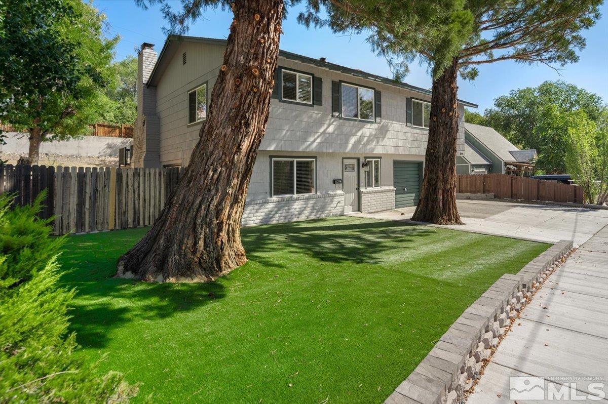 a front view of a house with a garden and tree