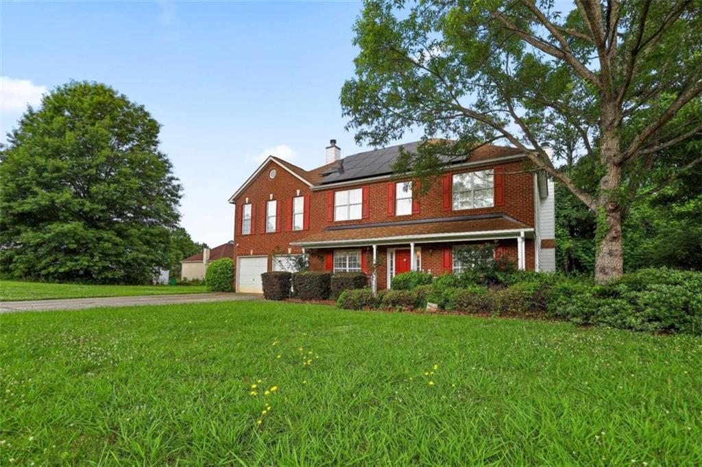 a view of a building next to a big yard and large trees