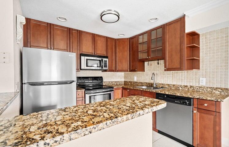 a kitchen with stainless steel appliances granite countertop a refrigerator stove top oven with a sink and dishwasher