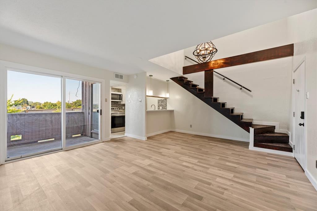 a view of a livingroom with wooden floor and stairs