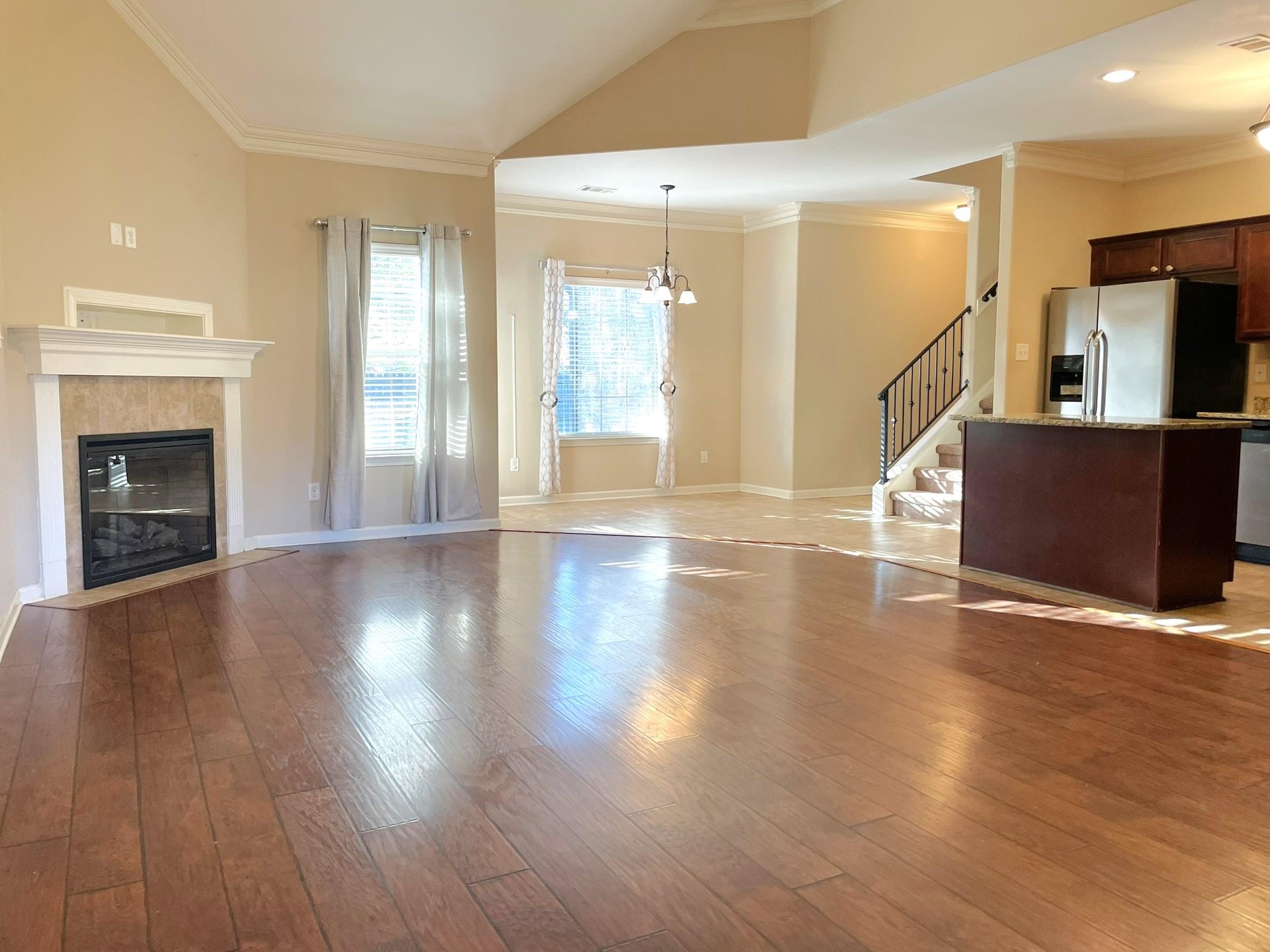 Unfurnished living room featuring a fireplace, an inviting chandelier, light hardwood / wood-style flooring, and ornamental molding