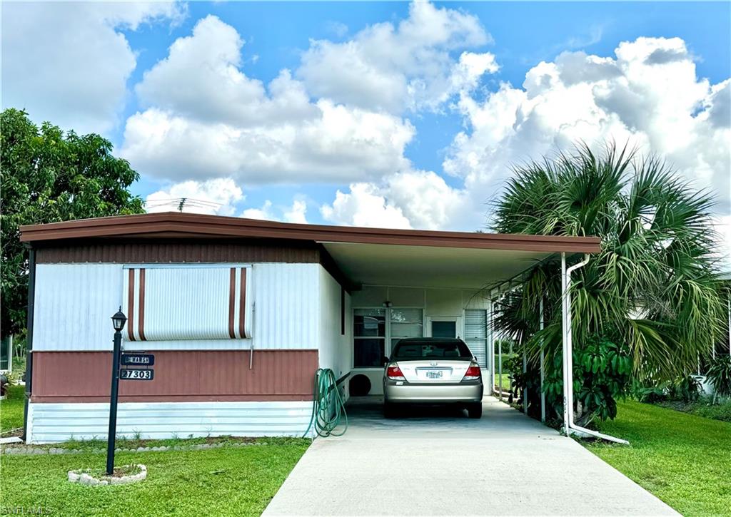 View of front of property with a front yard and a carport