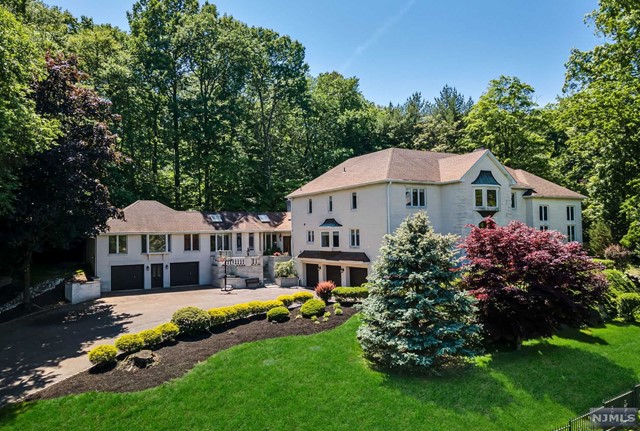 a front view of a house with garden and trees