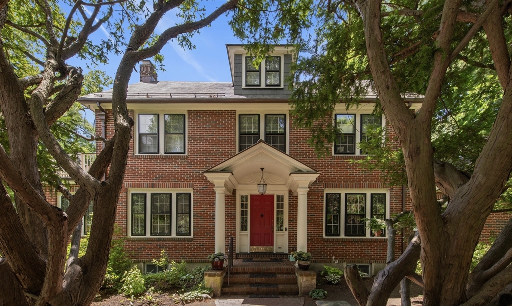 front view of a brick house with a large windows and a large tree