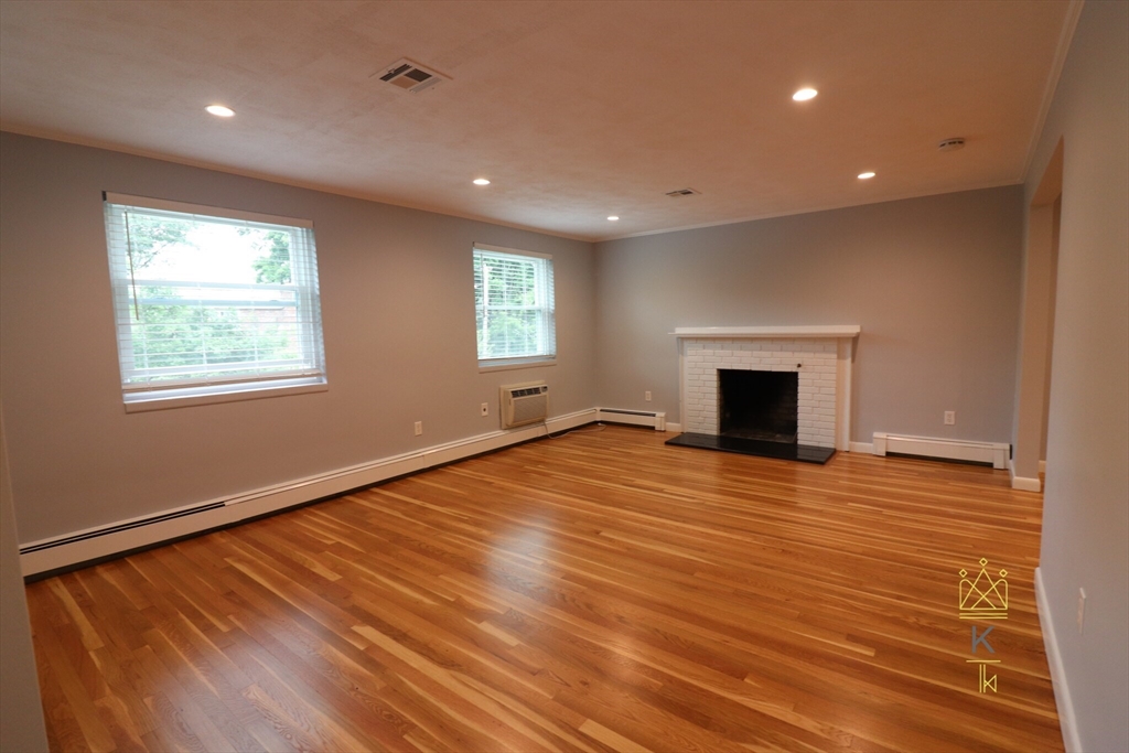 a view of empty room with wooden floor and fireplace