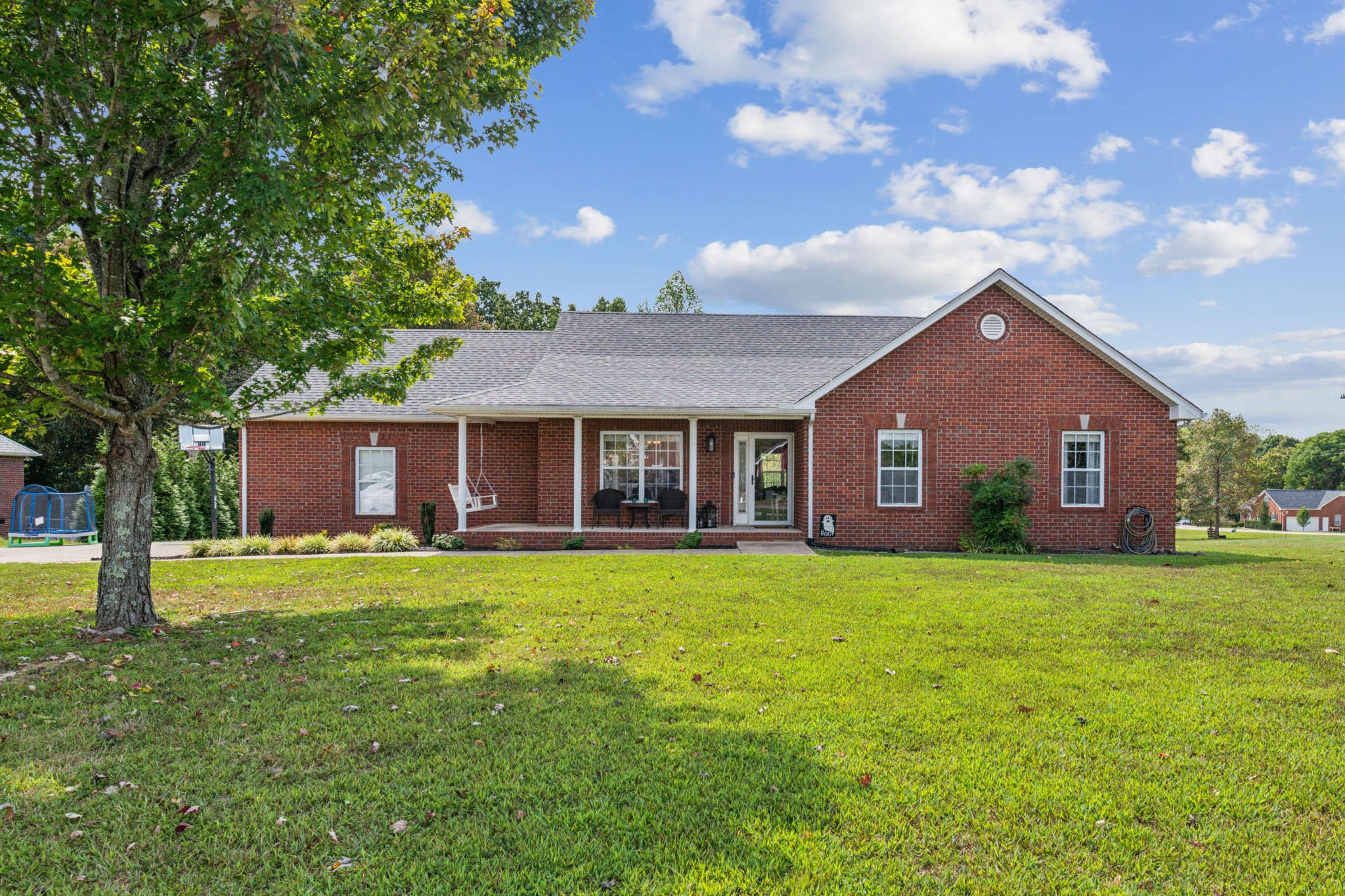 a front view of a house with a yard and trees