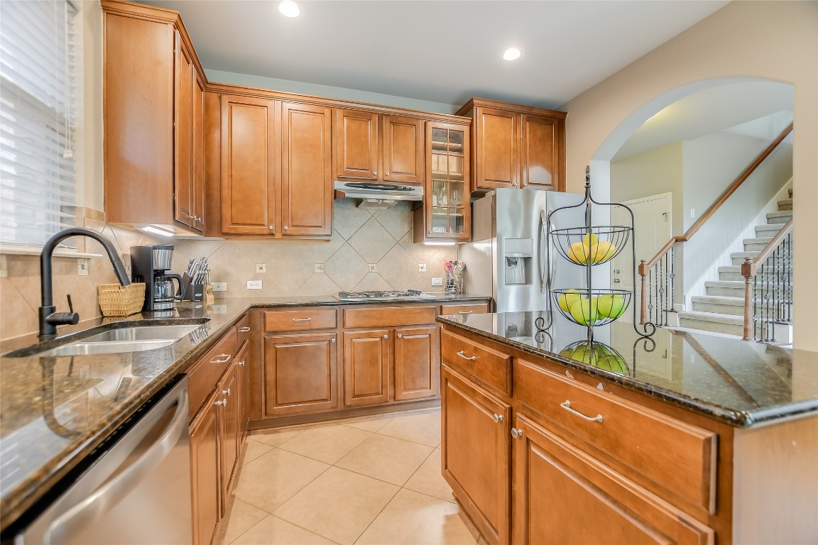 a kitchen with stainless steel appliances granite countertop a sink a stove cabinets counter space and a window