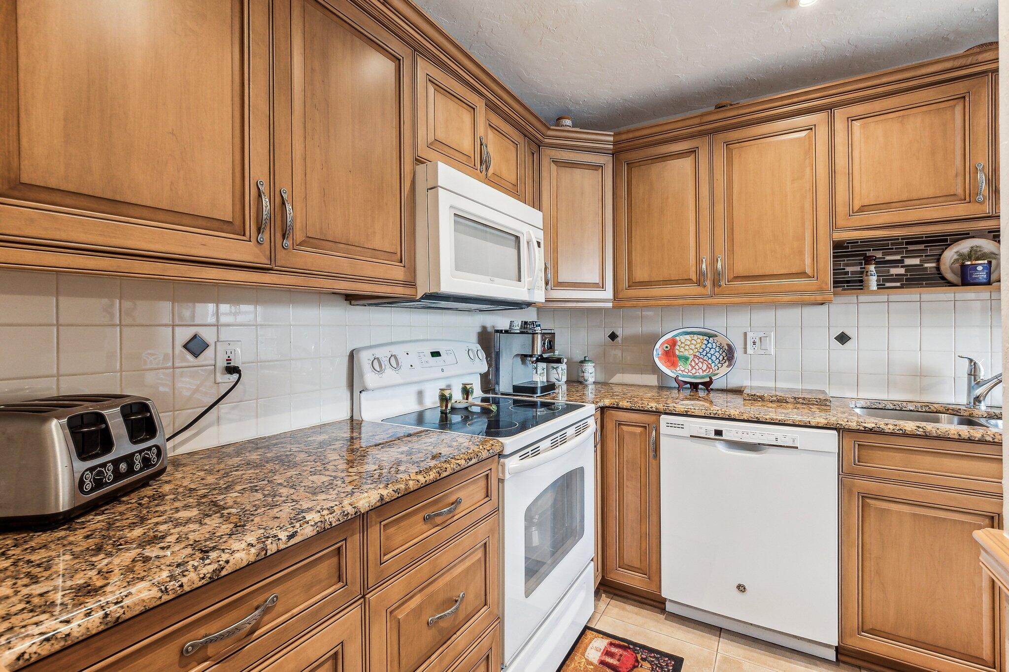 a kitchen with granite countertop a sink stainless steel appliances and cabinets