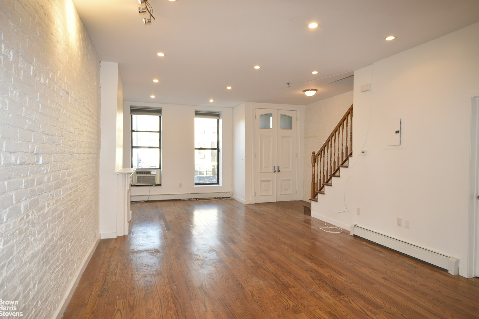 an entryway of an empty room with wooden floor and stairs