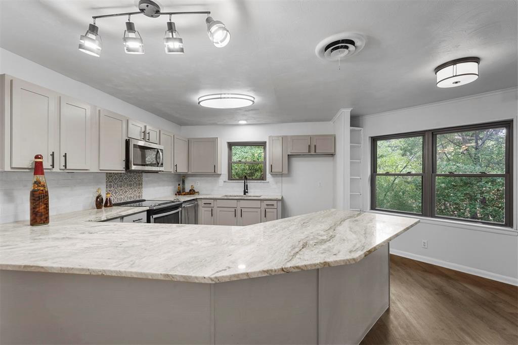 a view of a kitchen with granite countertop a sink window and cabinets