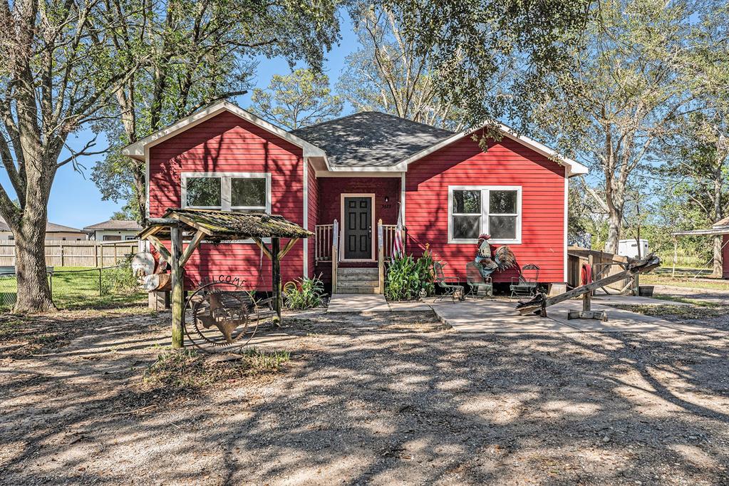 Charming single-story home with a rustic aesthetic, a welcoming front porch and a spacious yard with mature trees.