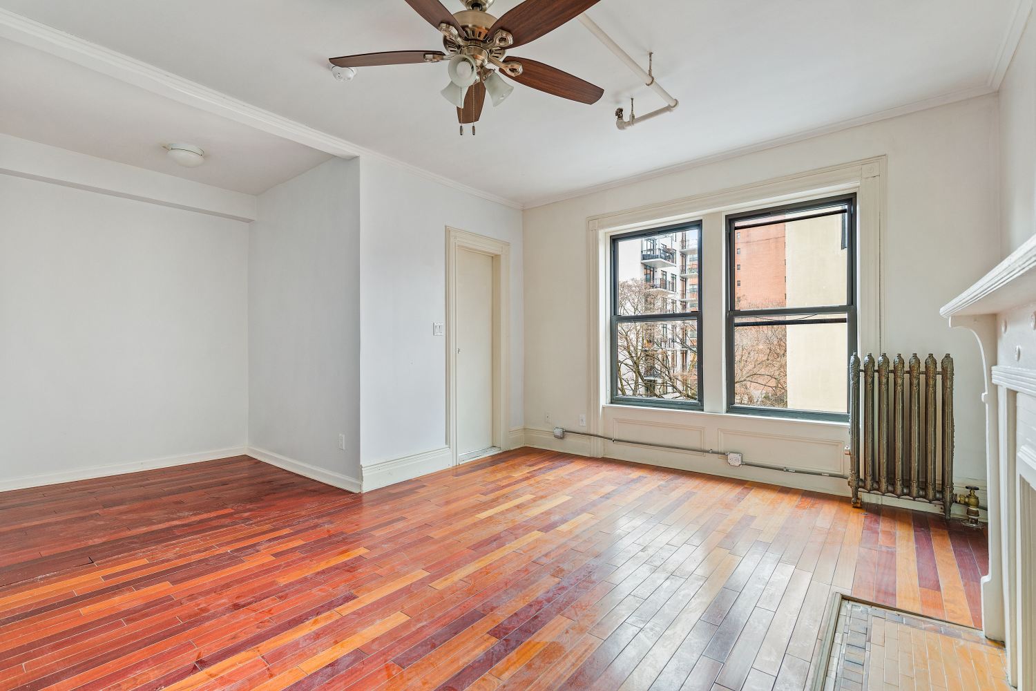 a view of an empty room with wooden floor and a window