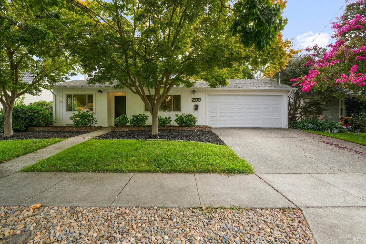 a front view of a house with a garden and trees