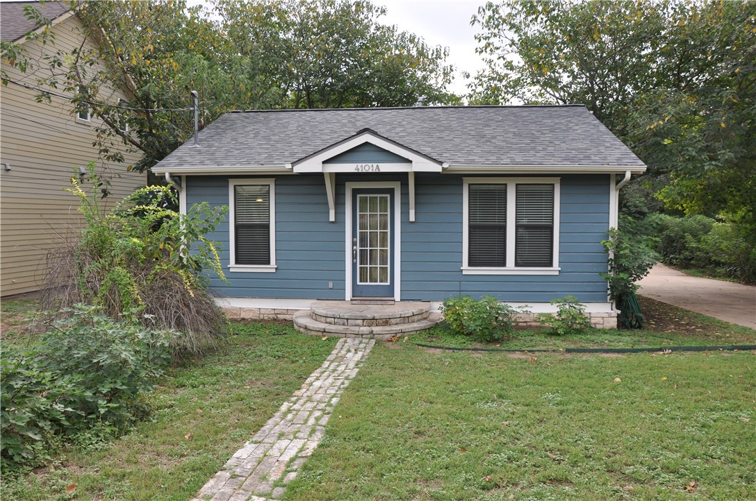 a aerial view of a house with yard and trees in the background