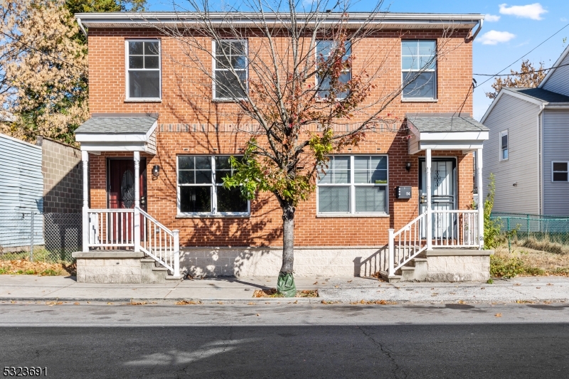 a front view of a house with a tree