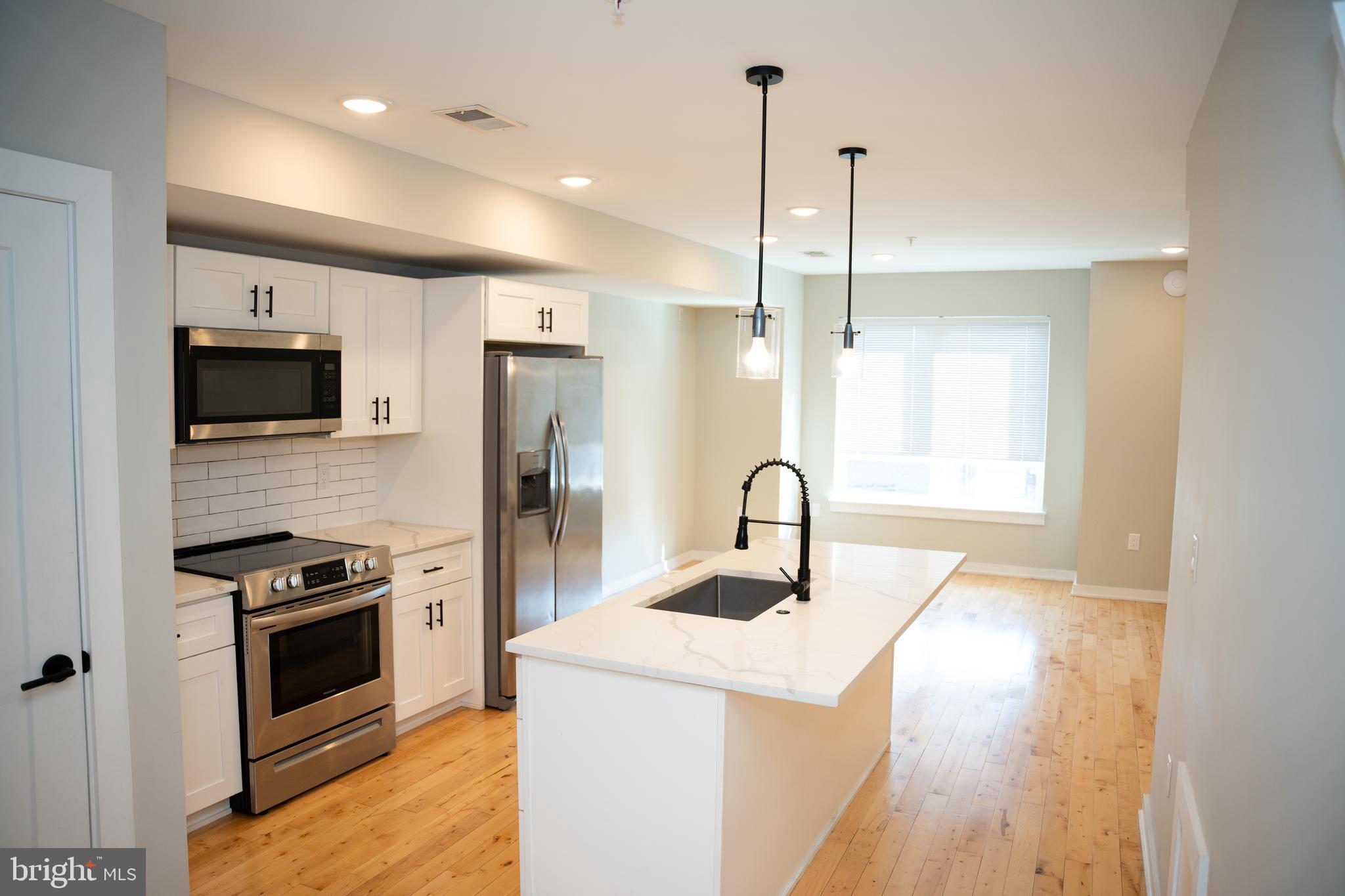 a kitchen with stainless steel appliances kitchen island a sink a stove and a wooden floors