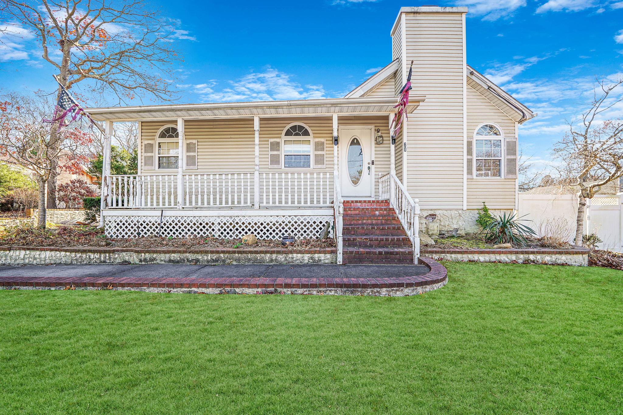 View of front of property featuring covered porch and a front yard