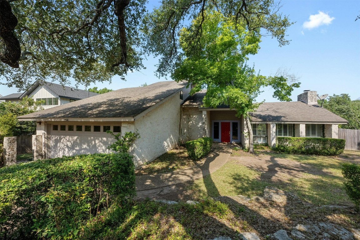 a view of a house with brick walls plants and large tree