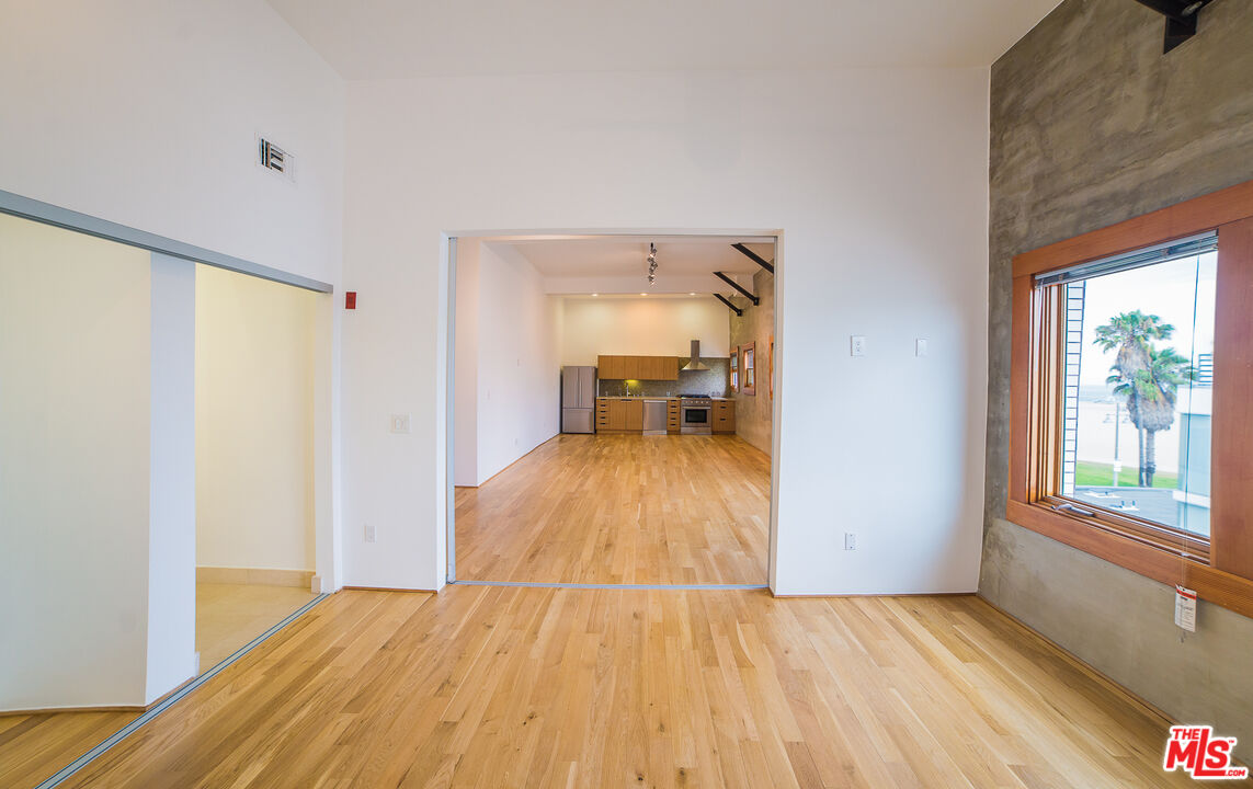 a view of empty room with wooden floor and fan