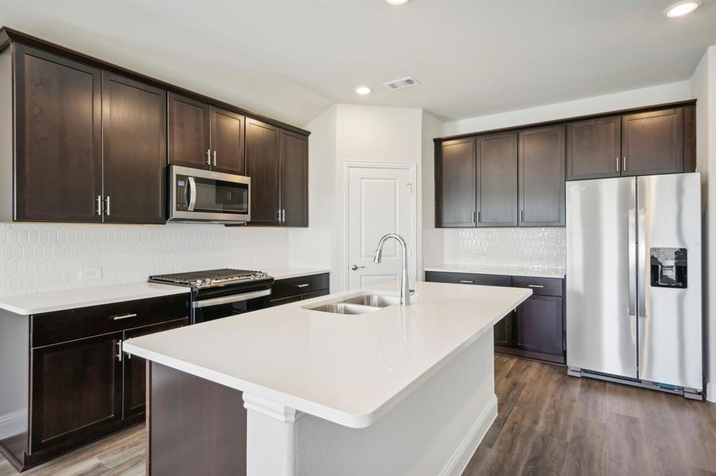 a kitchen with stainless steel appliances a sink stove refrigerator and cabinets