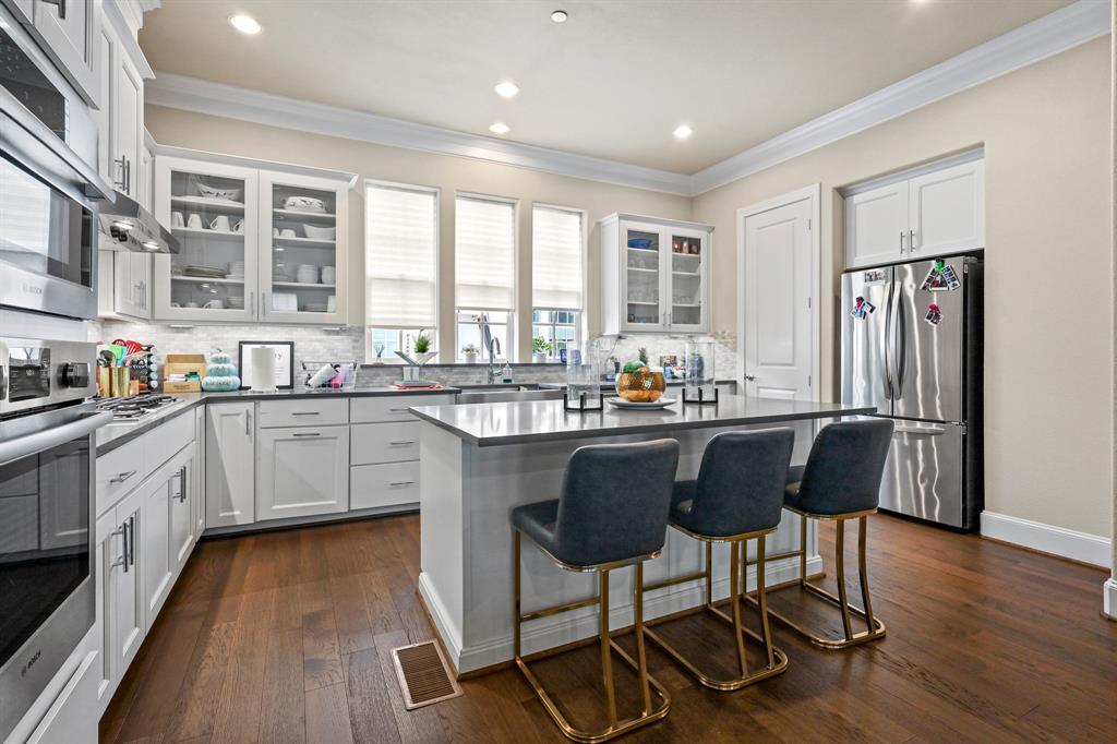 a kitchen with stainless steel appliances granite countertop a stove a refrigerator a sink dishwasher a dining table and chairs with wooden floor