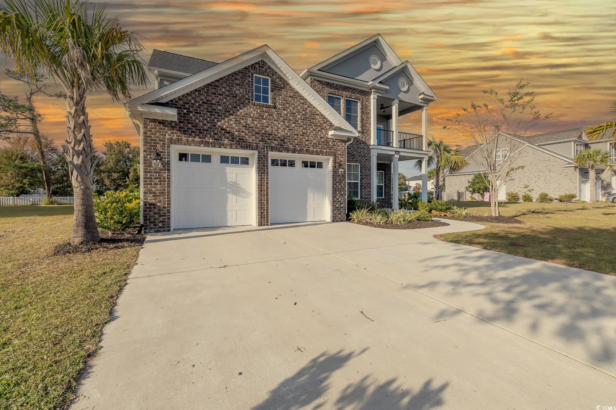 View of front of home with a garage, a balcony, an