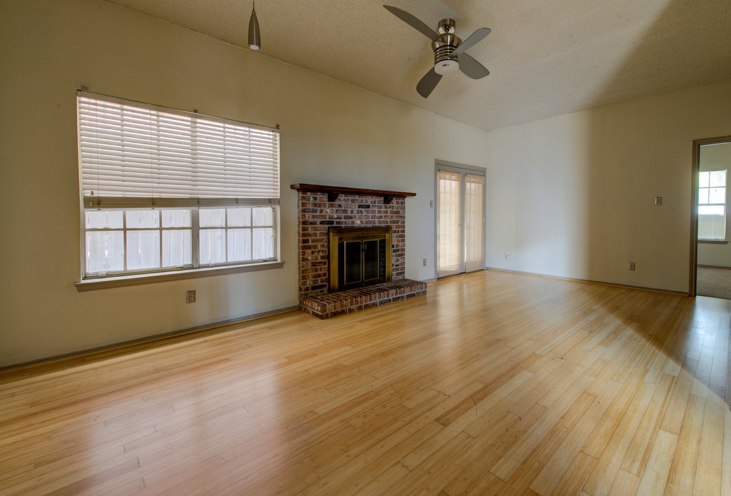 an empty room with wooden floor fireplace and windows