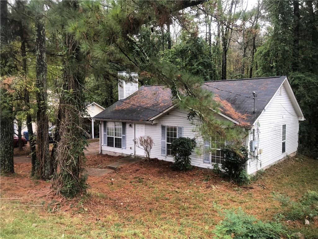 a view of house with a yard and large tree