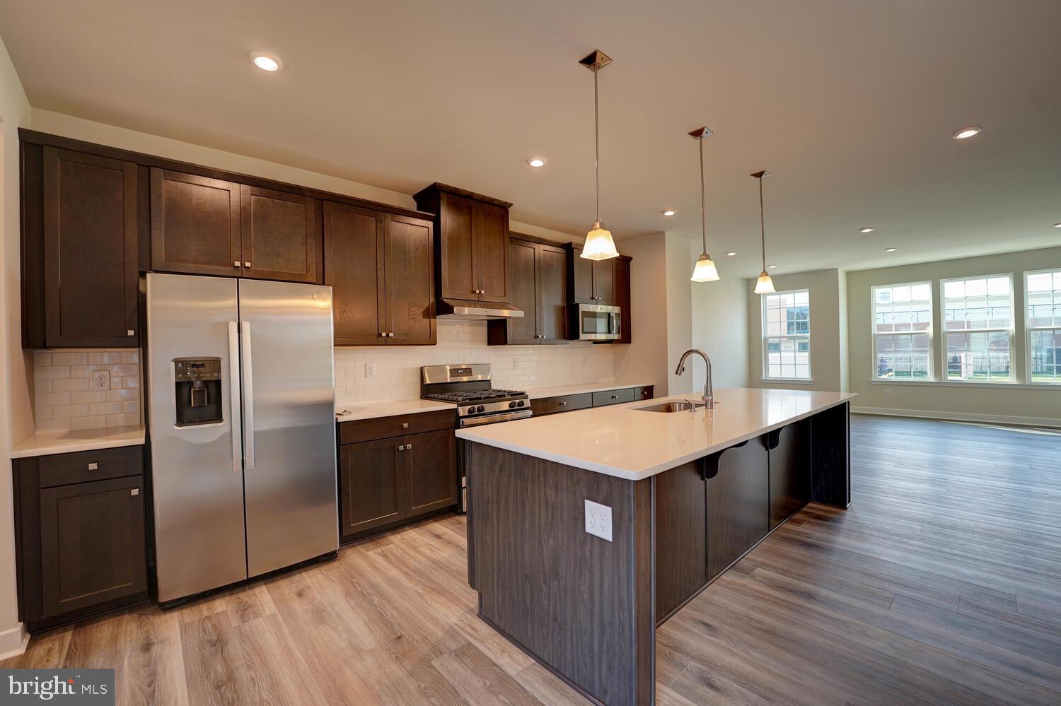 a large kitchen with a center island wooden floor stainless steel appliances and windows