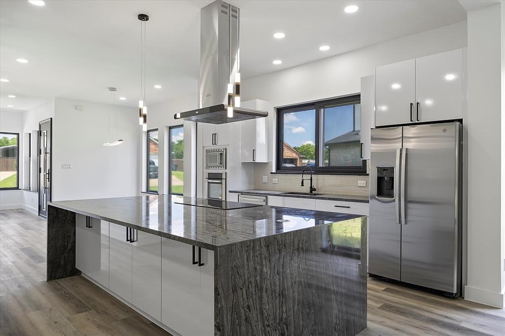 a kitchen with kitchen island a refrigerator a sink and a stove