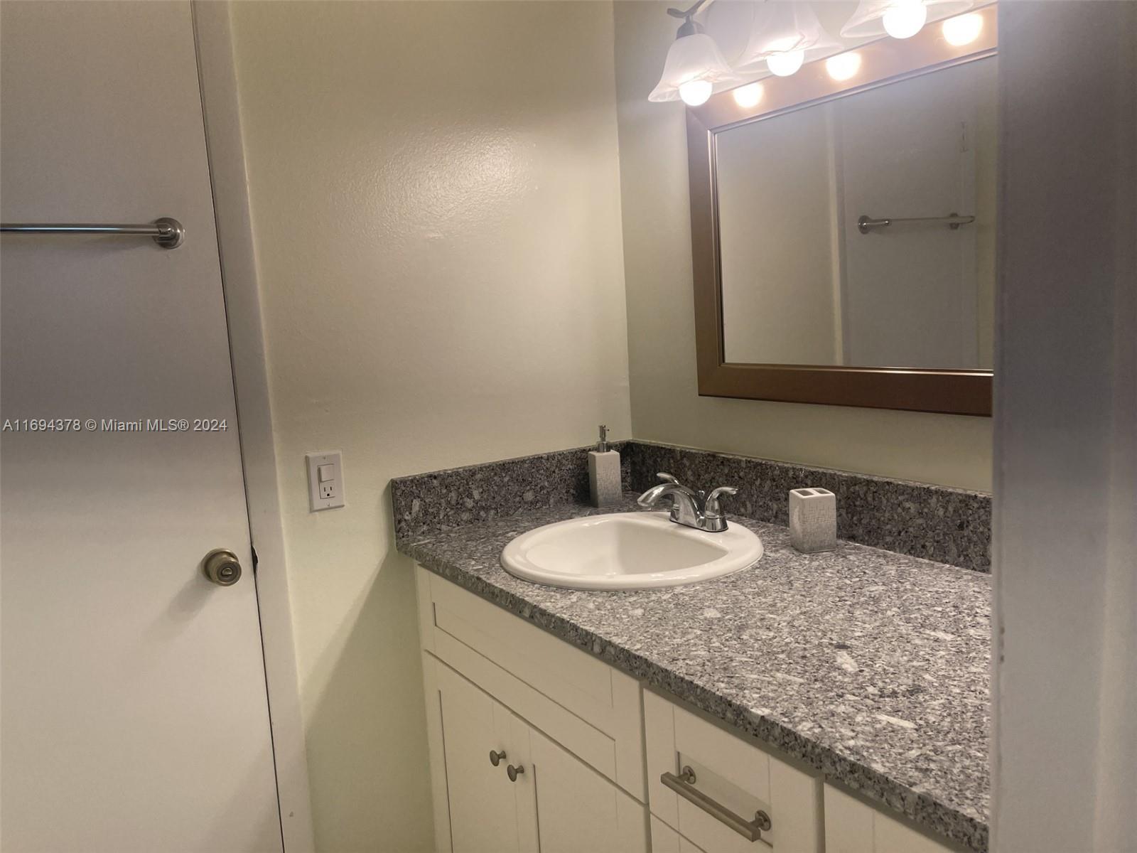 a bathroom with a granite countertop sink and a mirror