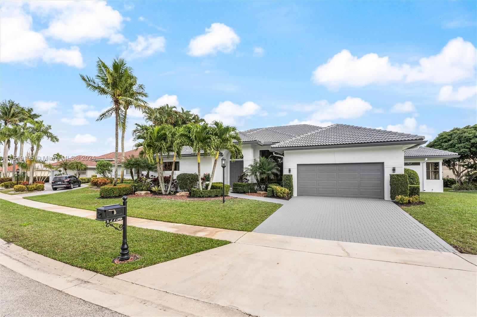 a white house with a yard and palm trees