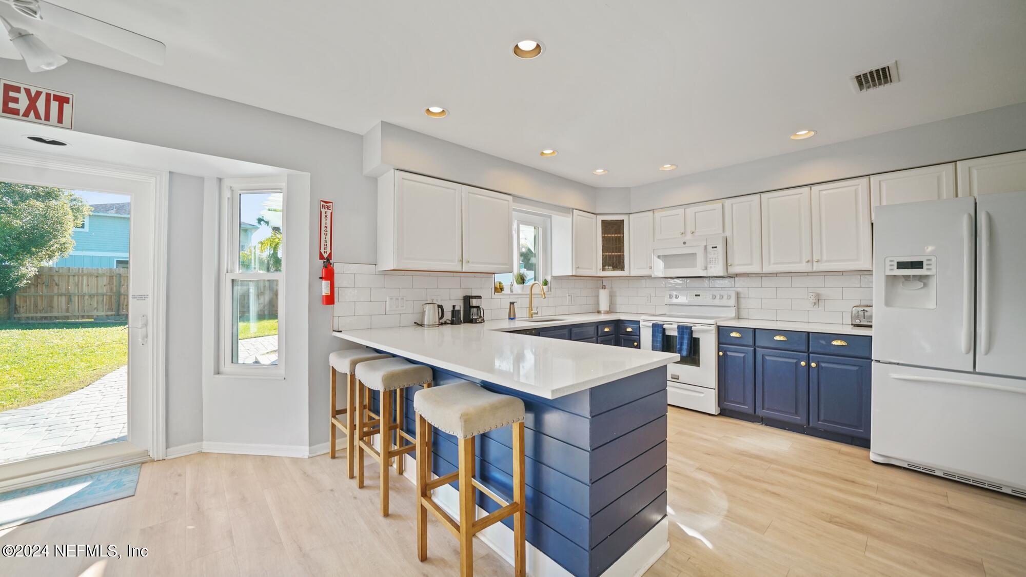 a kitchen with a sink a stove a refrigerator cabinets and a wooden floor