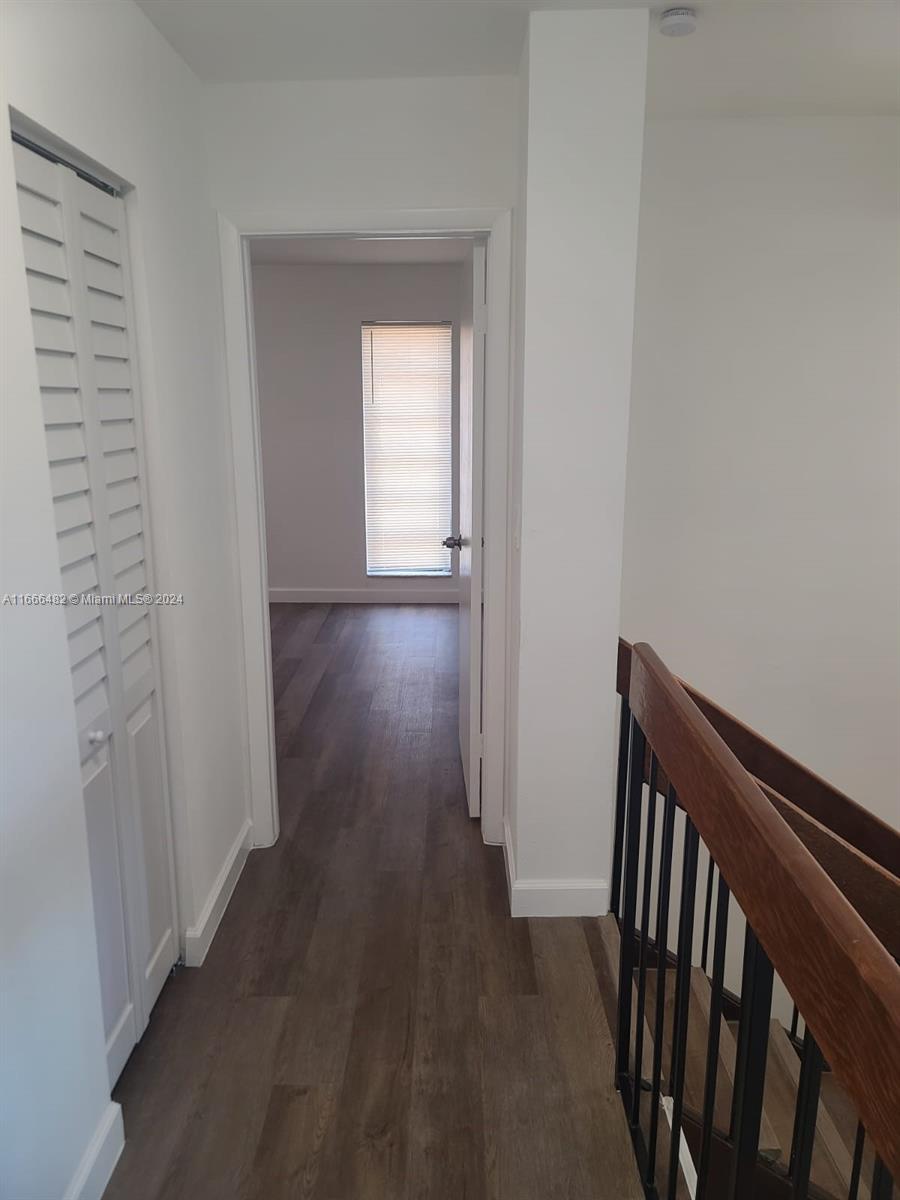 a view of a hallway with wooden floor and closet