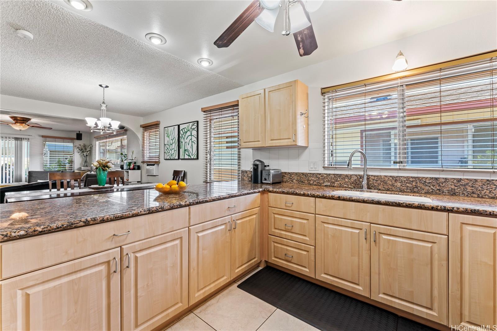 a kitchen with granite countertop white cabinets white appliances a sink and a window