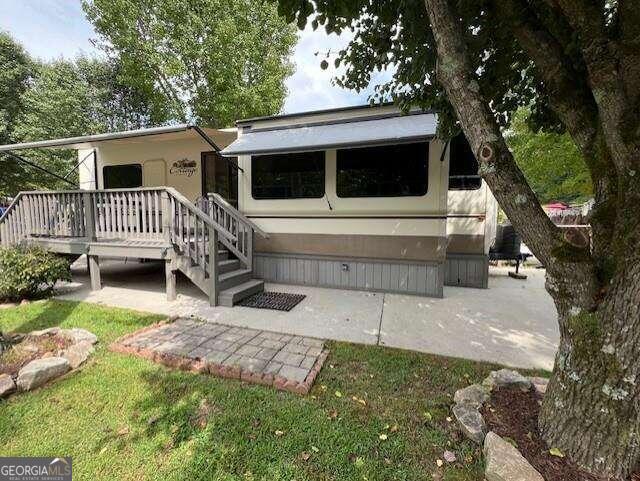 a view of a house with a yard deck and a large tree