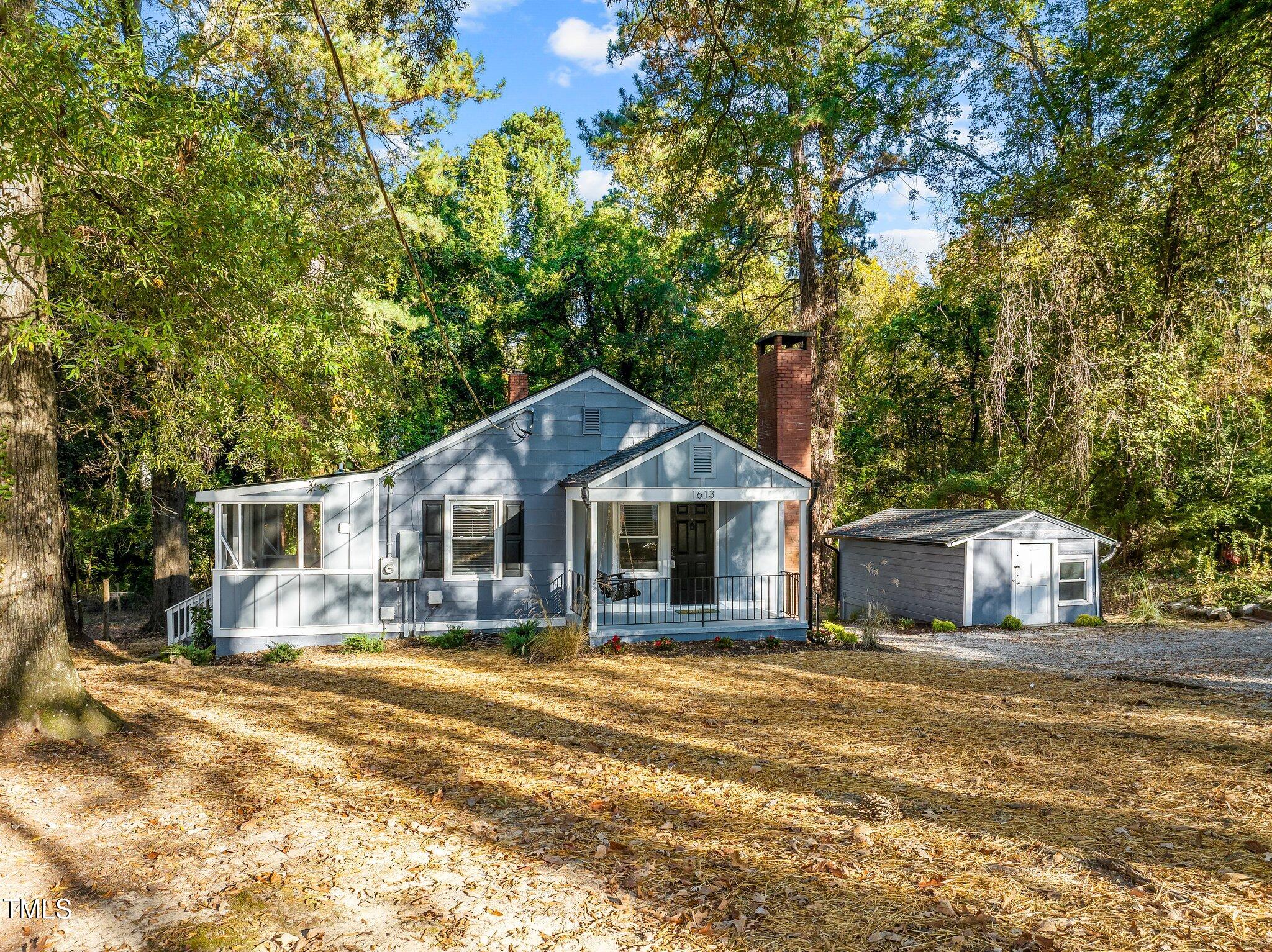 a front view of a house with a yard and large trees