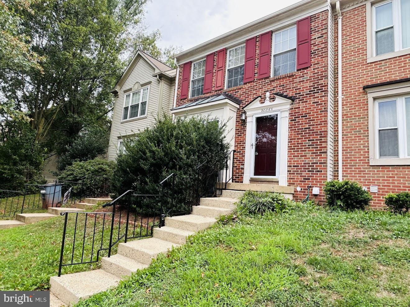 a view of a brick house with a yard and plants