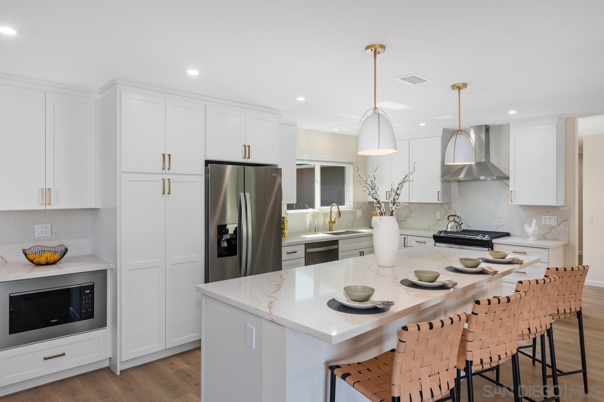 a kitchen that has a lot of white cabinets and stainless steel appliances