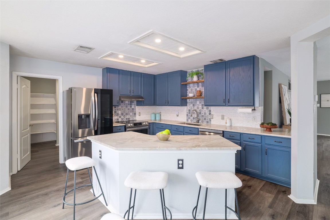 a kitchen with stainless steel appliances a dining table chairs refrigerator and cabinets