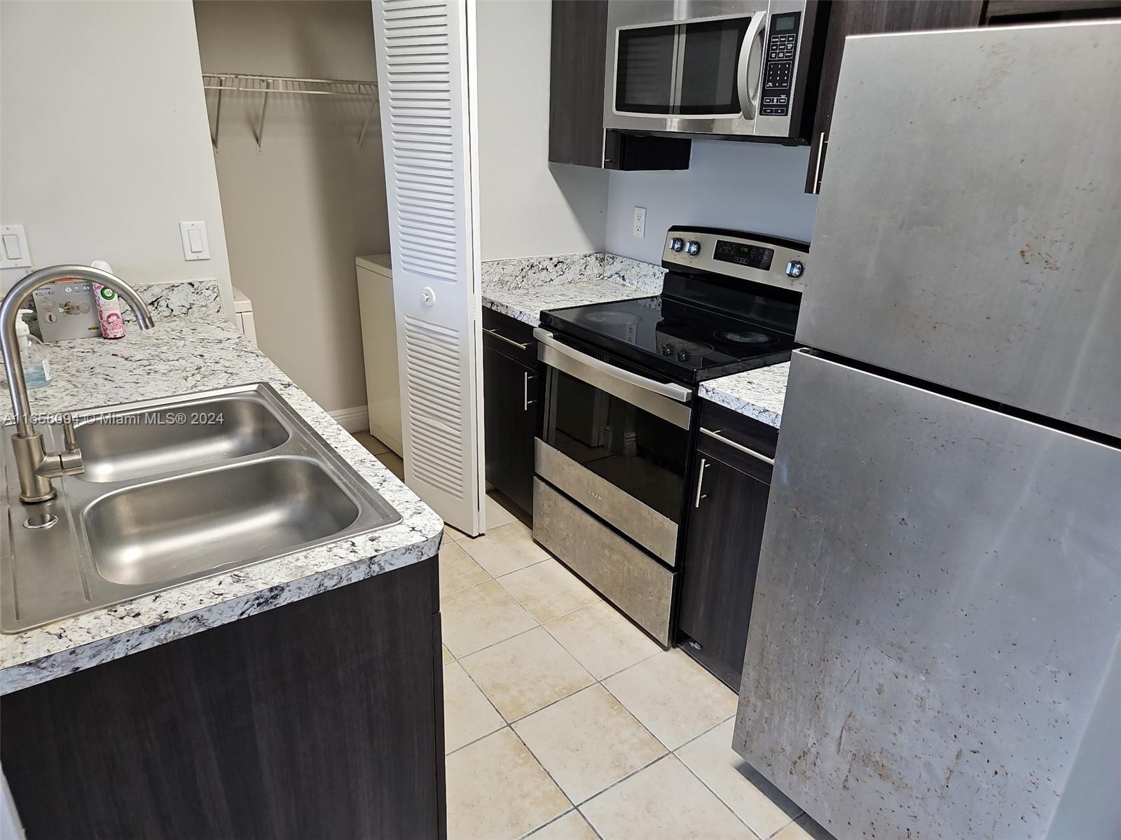 a kitchen with granite countertop a sink stove and refrigerator