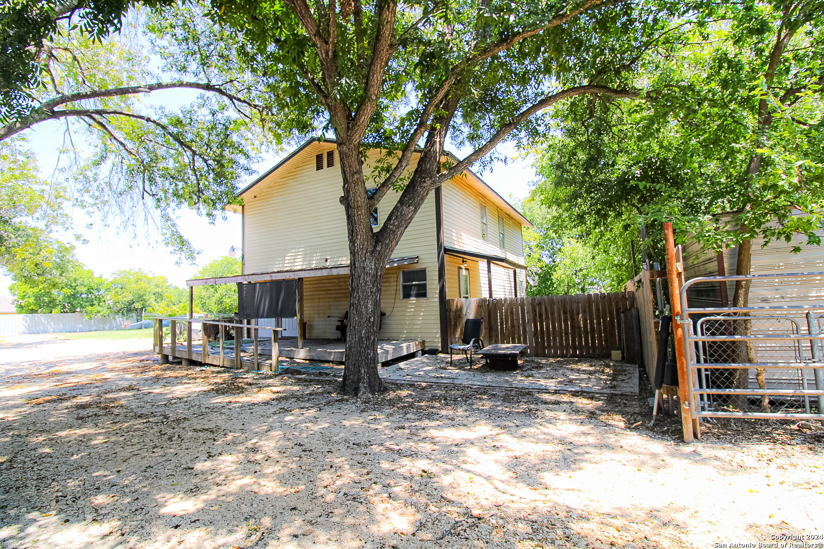 a backyard of a house with barbeque and a large tree