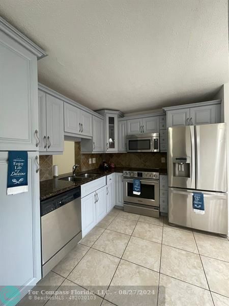 a kitchen with granite countertop a refrigerator and a stove top oven