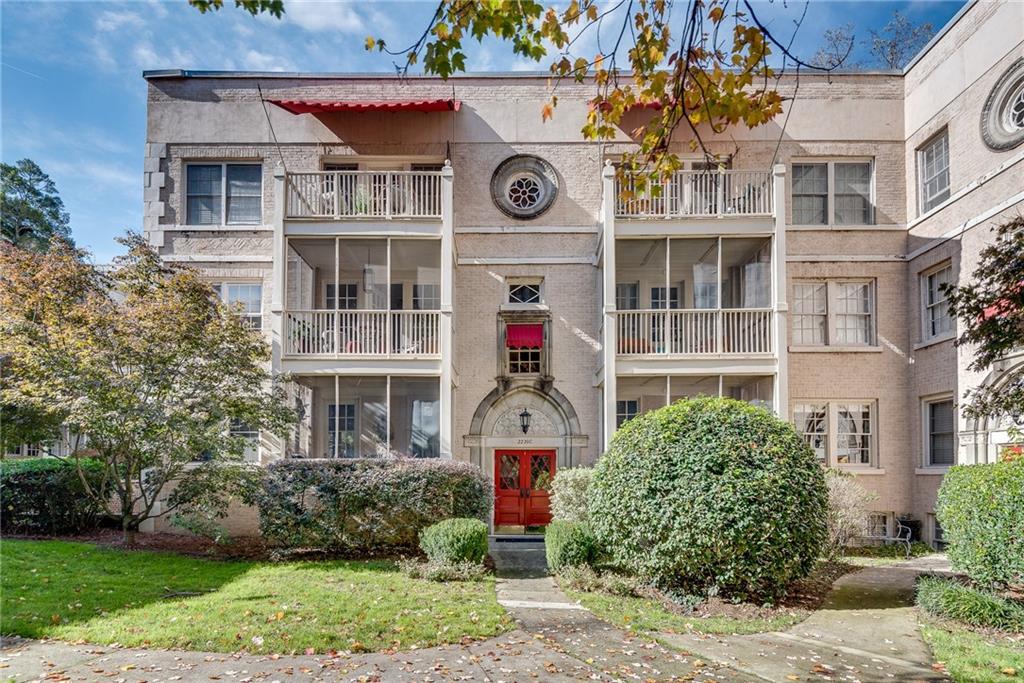 a front view of a residential apartment building with a yard and potted plants