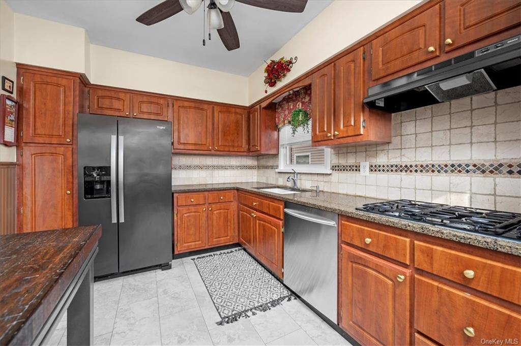 Kitchen with stainless steel appliances, sink, tasteful backsplash, ceiling fan, and wood counters