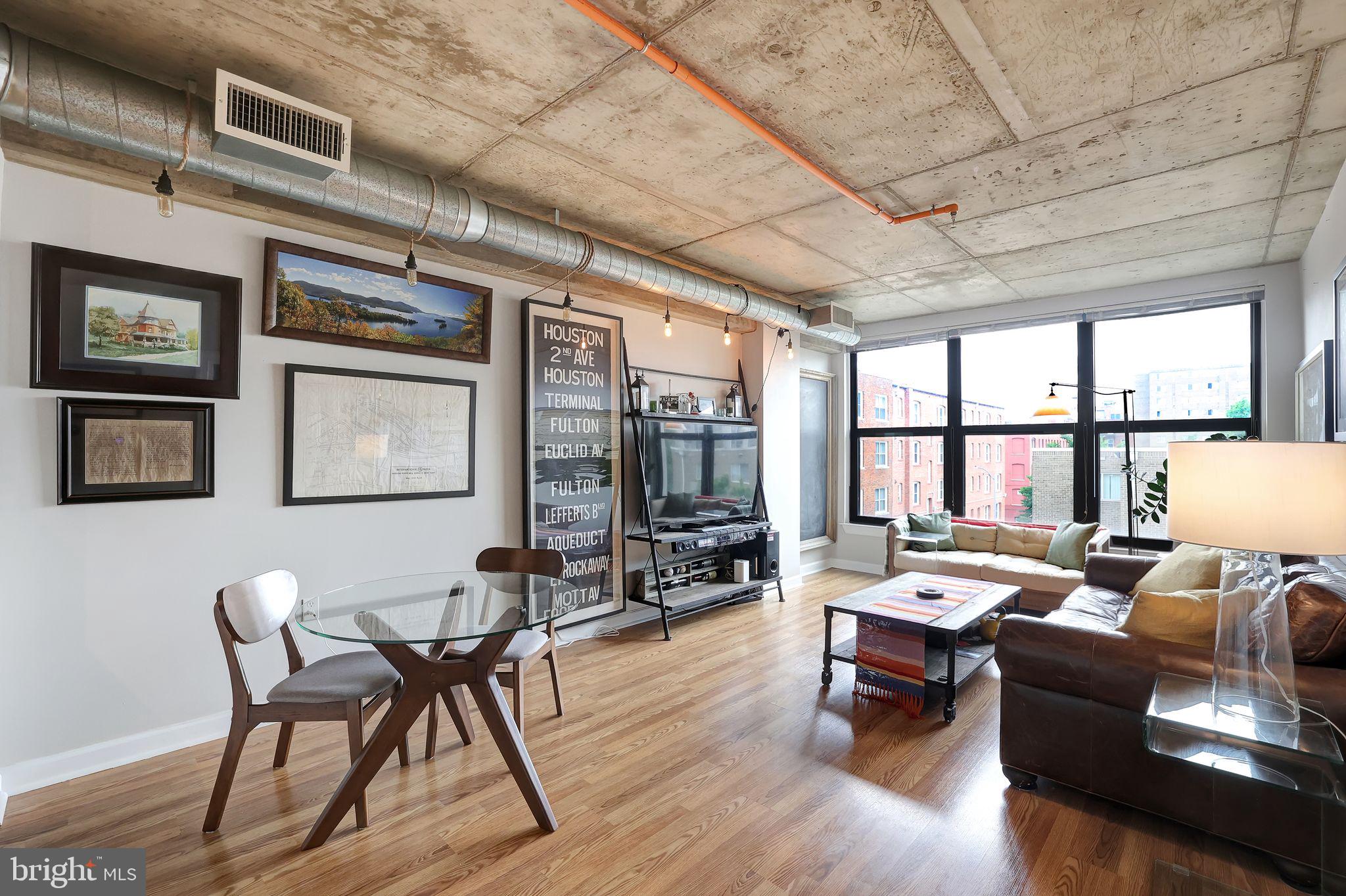 a living room with furniture a flat screen tv and floor to ceiling window